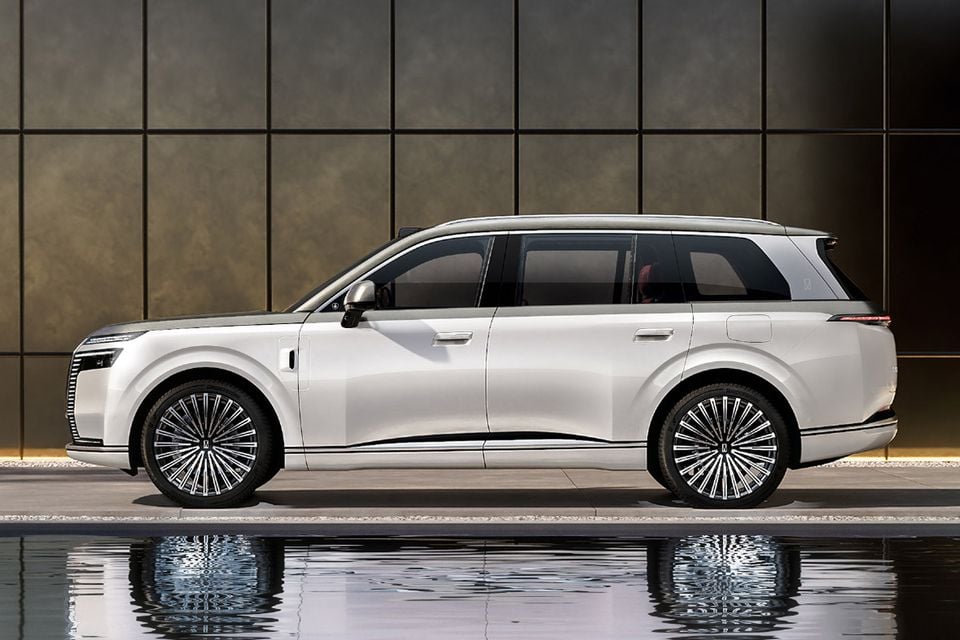 A white 2027 Avatr T09 large SUV seen from the side, parked against a dark panelled wall with a reflective surface below