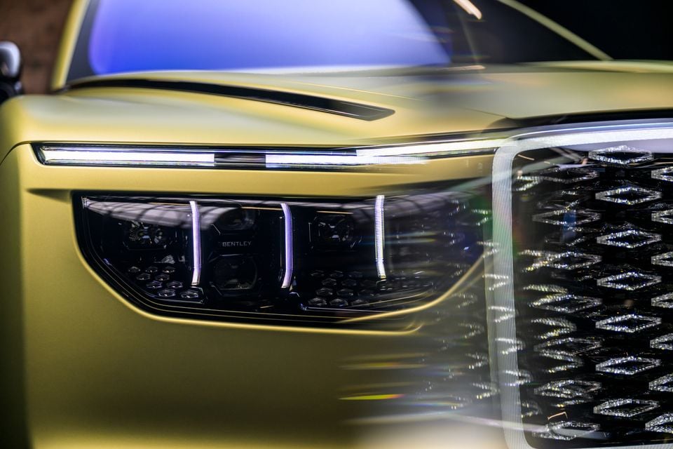 Close-up of the headlight and front grille of a Bentley Torcal in a yellow-green finish, showing detailed LED lighting and diamond-pattern grille