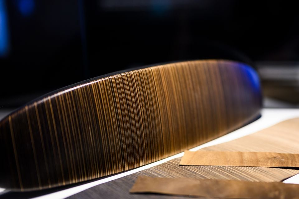 Close-up of a wood veneer trim piece, likely an interior component from a Bentley Torcal concept, showing fine linear grain detail under studio lighting.