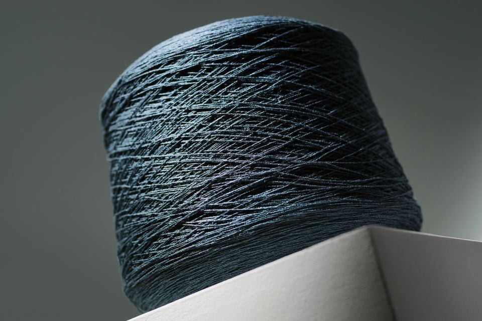 A close-up of a spool of dark blue thread or fibre, likely a teaser image related to the Bentley Torcal.