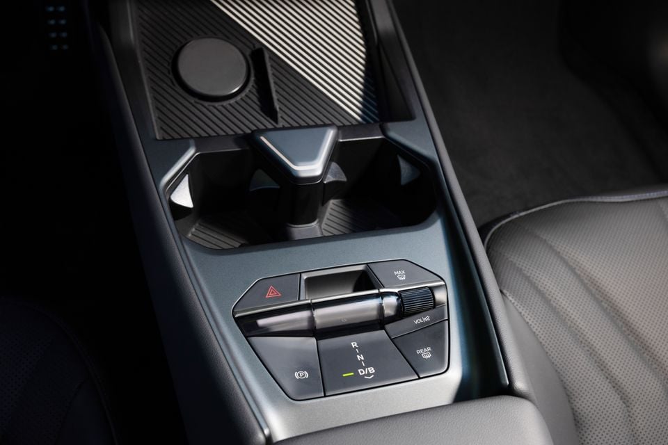 Centre console of the 2027 BMW i3 with a crystal-style gear selector, hazard light, park brake, demister and volume controls beside cupholders