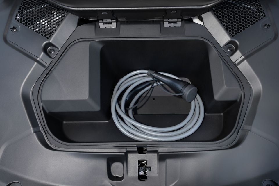 Front storage compartment of a 2027 BMW i3 50 with a coiled grey charging cable inside