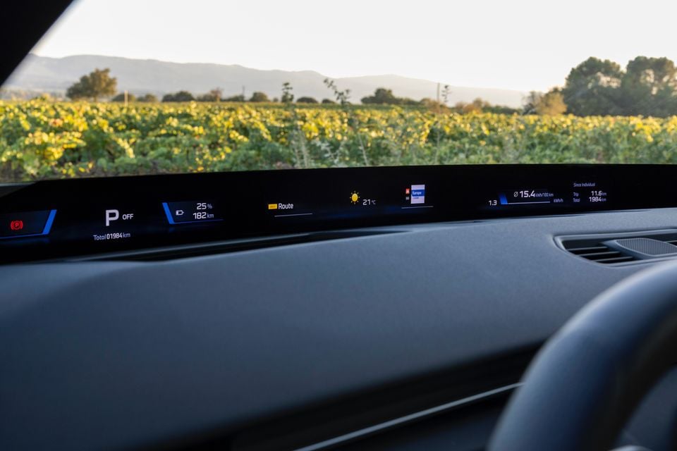 BMW iX3 panoramic head-up display strip at the base of the windscreen showing range, temperature and efficiency, with a vineyard beyond