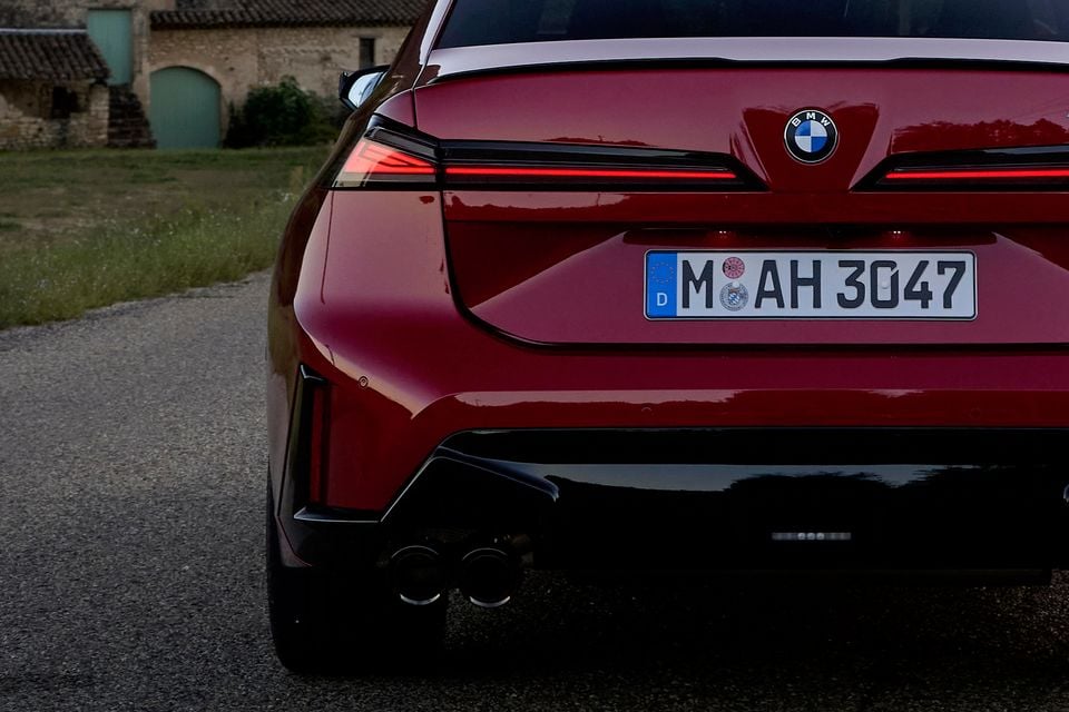 Rear of a red 2027 BMW M350 3 Series sedan showing slim LED tail-lights, BMW badge and quad exhaust tips