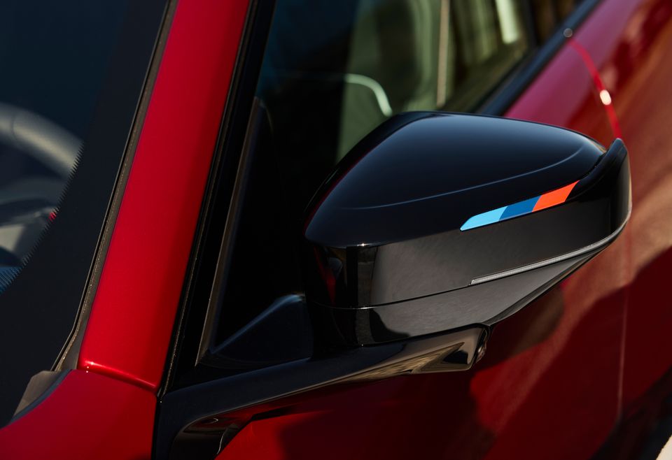 Close-up of the black side mirror with an M-colour stripe on a red 2027 BMW M350 xDrive.