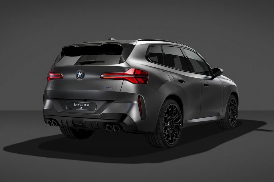 A grey BMW X3 M50 SUV photographed in a studio, viewed from the rear quarter angle.