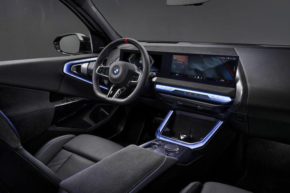 The interior of a 2027 BMW X3 M50 shows the curved dashboard display, steering wheel and illuminated centre console.