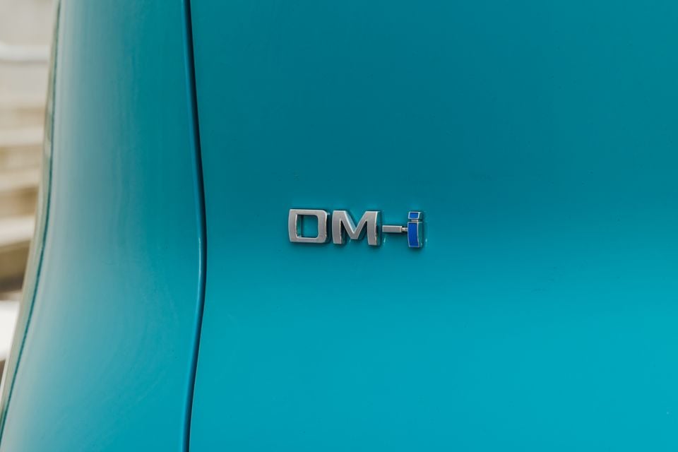 Close-up of a "DM-i" badge on the teal-coloured bodywork of a BYD Atto 2 DM-i.