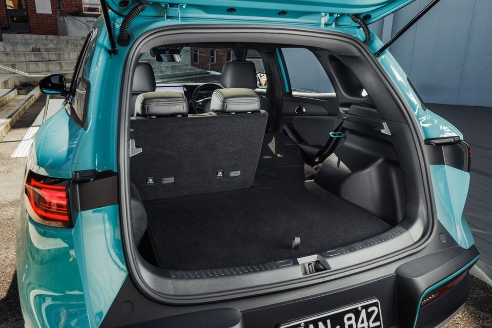 The open boot of a teal 2027 BYD Atto 2 shows the empty cargo area with the rear seats folded flat on one side.