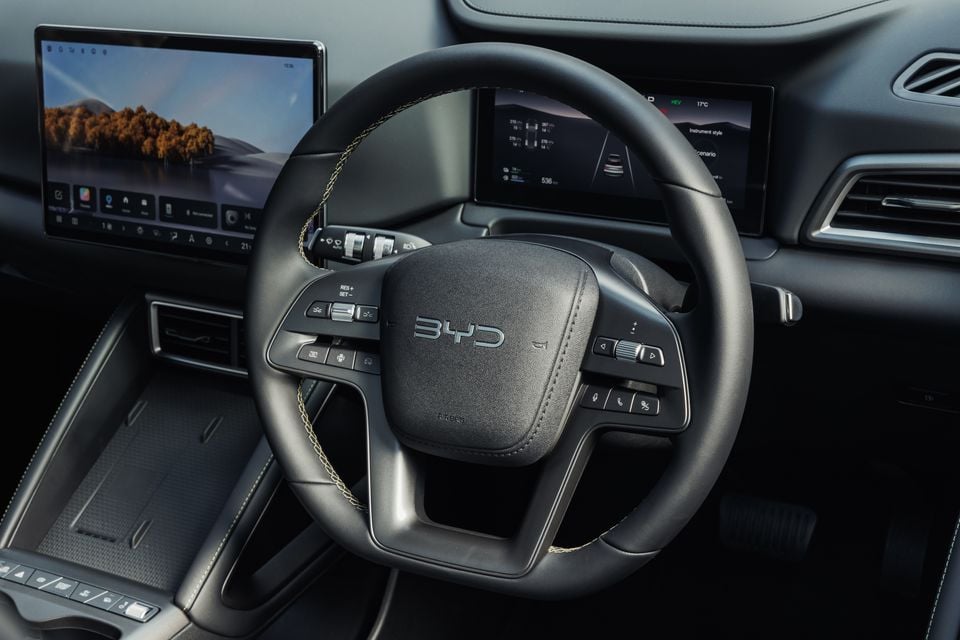 Close-up of the BYD Atto 2's steering wheel with controls, showing the digital instrument cluster and central touchscreen behind it