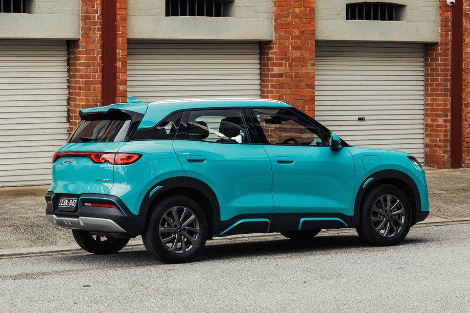 A teal BYD Atto 2 SUV parked on a street, seen from the rear side angle