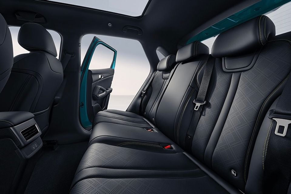 The black leather rear seats of a 2027 BYD Atto 2 DM-i show a panoramic sunroof and open door with teal-coloured trim.