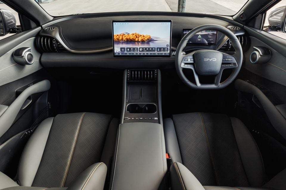 The interior of a BYD Atto 3 Evo shows the dashboard, steering wheel, centre touchscreen and front seats.