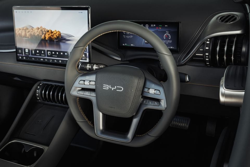The steering wheel and dashboard of a BYD Atto 3, showing the digital instrument display and touchscreen infotainment system