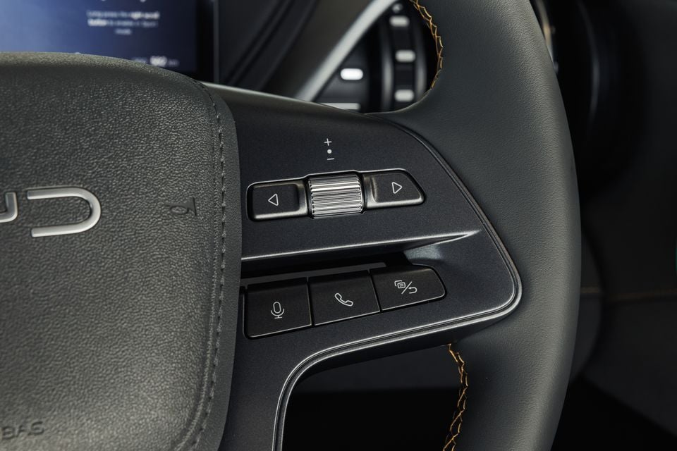 Close-up of the steering wheel controls on a 2027 BYD Atto 3 Evo, showing volume, scroll and voice/phone buttons