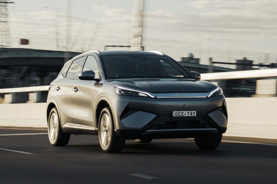 A silver BYD Atto 3 SUV driving on an elevated highway, viewed from the front quarter