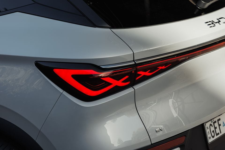 Close-up of the illuminated red taillight on the rear of a white BYD Atto 3 electric SUV.