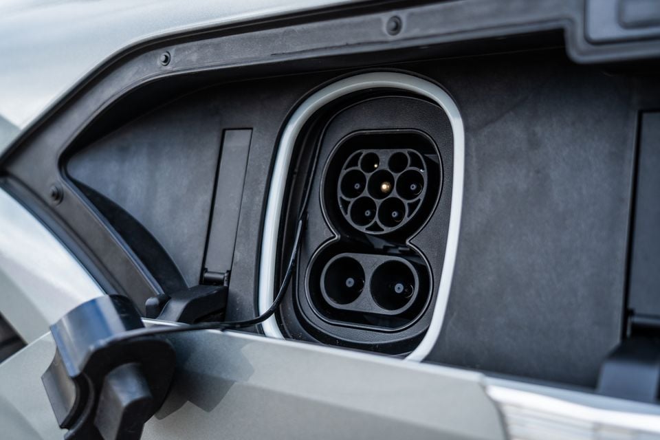 Close-up of a CCS (Combined Charging System) Type 2 charging port on a silver electric vehicle, with a charging cable partially visible