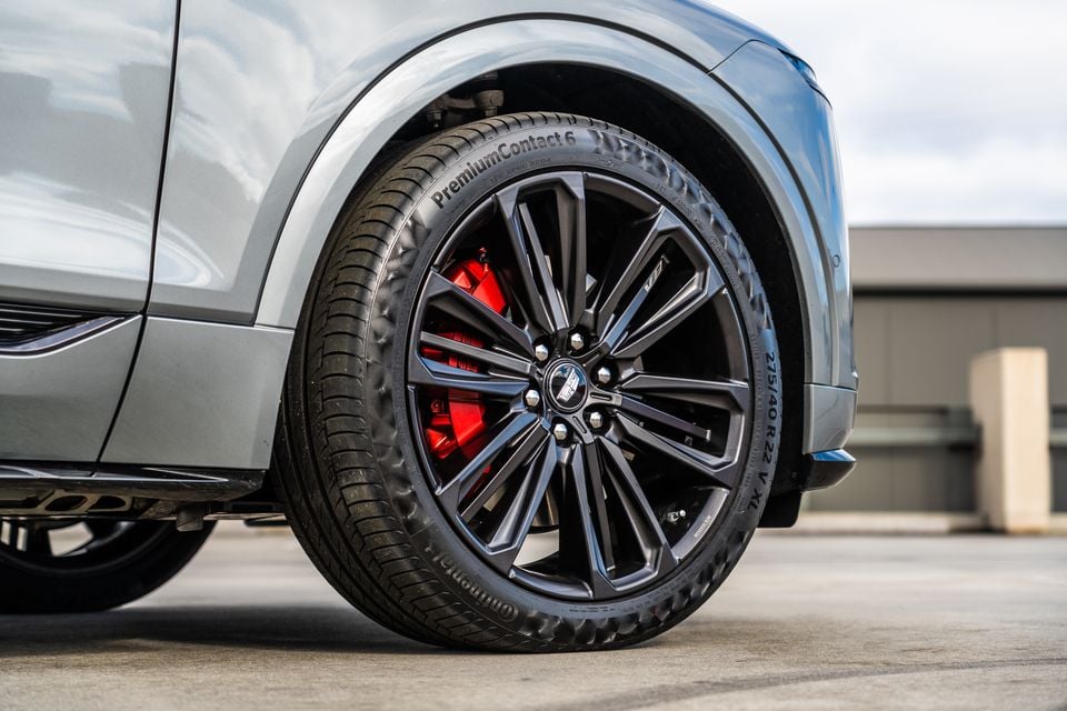 Close-up of a dark multi-spoke 22-inch alloy wheel with red brake callipers and Continental PremiumContact 6 tyres on a grey Cadillac Lyriq V SUV