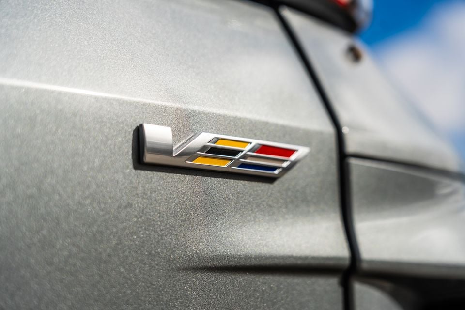 Close-up of the Cadillac V-Series badge on the silver body panel of a 2027 Cadillac Lyriq V