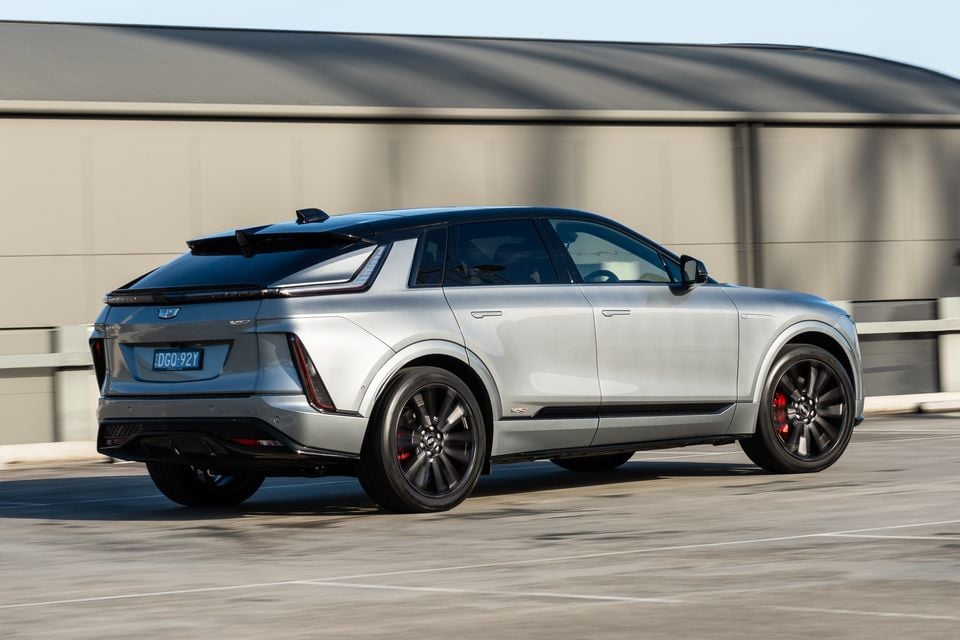 A silver 2027 Cadillac Lyriq-V SUV seen from the rear three-quarter angle in a car park