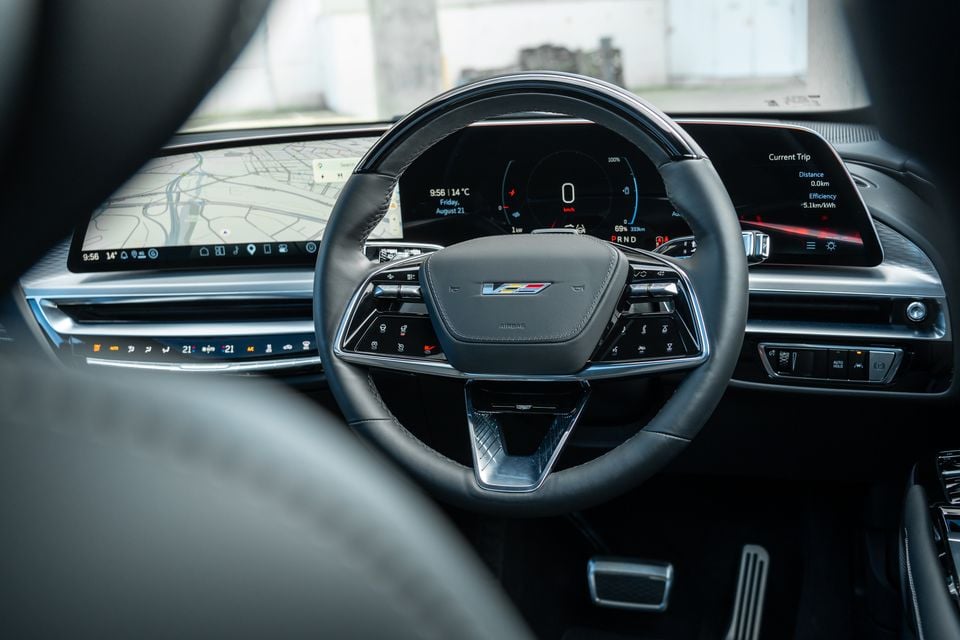 Interior of a Cadillac Lyriq V showing the steering wheel, digital instrument cluster, and large infotainment display with navigation