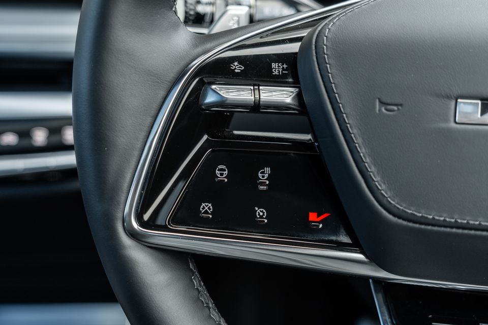 Close-up of the left steering wheel spoke controls on a 2027 Cadillac LYRIQ-V, showing cruise control, steering wheel heating, and driver assistance buttons