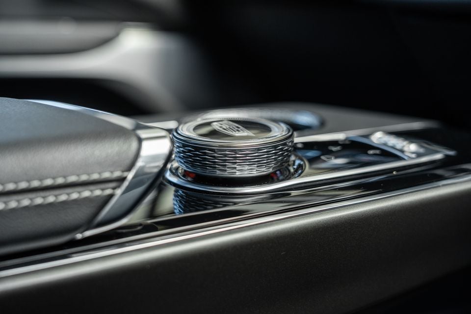 Close-up of the chrome rotary dial on the centre console of a 2027 Cadillac LYRIQ-V, featuring a knurled finish and Cadillac logo on top