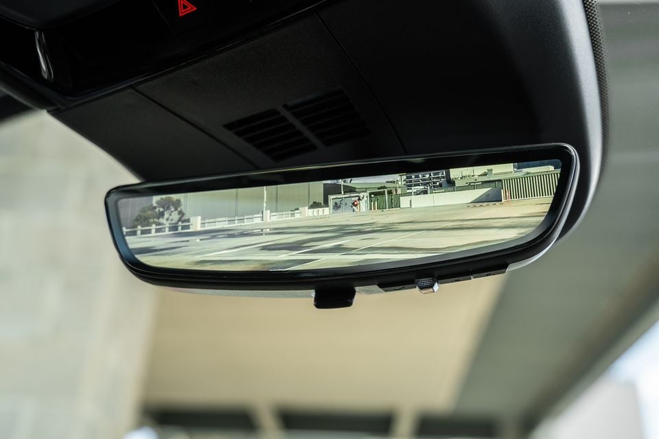 Close-up of a digital rear-view mirror inside a Cadillac Lyriq, displaying a wide-angle camera view of a car park behind the vehicle