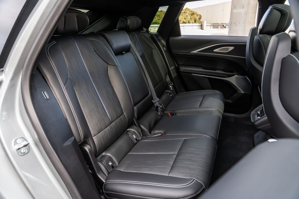 The rear seat interior of a Cadillac Lyriq showing black leather upholstery with contrast stitching and a three-seat bench layout