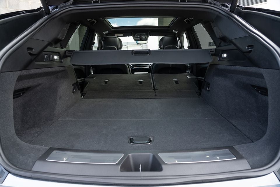The open boot of a 2027 Cadillac LYRIQ SUV showing a spacious carpeted cargo area with rear seats folded flat and a retractable cargo cover