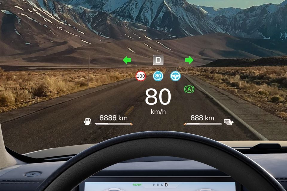 Head-up display showing speed, navigation and driver assist information projected onto the windscreen of a Chery Stockman, with a mountain road visible ahead