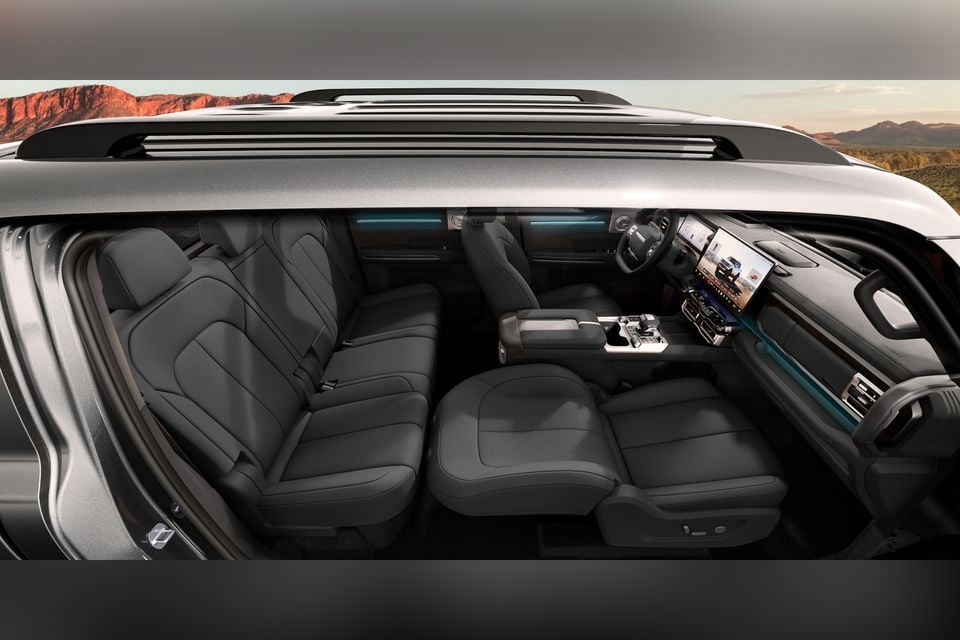 Interior of the 2027 Chery Stockman SUV showing dark upholstered front and rear seats, large touchscreen infotainment display, centre console, and ambient lighting, viewed from the side with doors removed