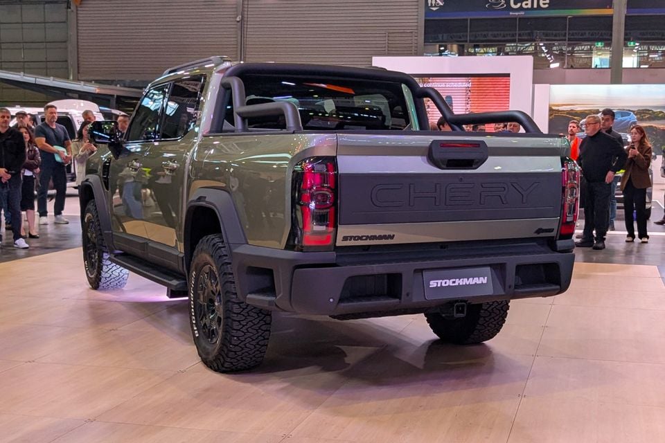 A green Chery Stockman ute with a roll bar, shown from the rear at a motor show with onlookers around it