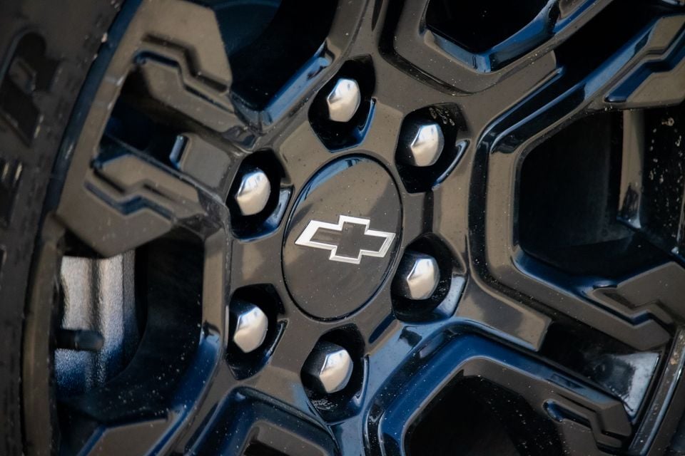 Close-up of a black alloy wheel on a Chevrolet Silverado ZR2, showing the Chevrolet bowtie centre cap and chrome lug nuts