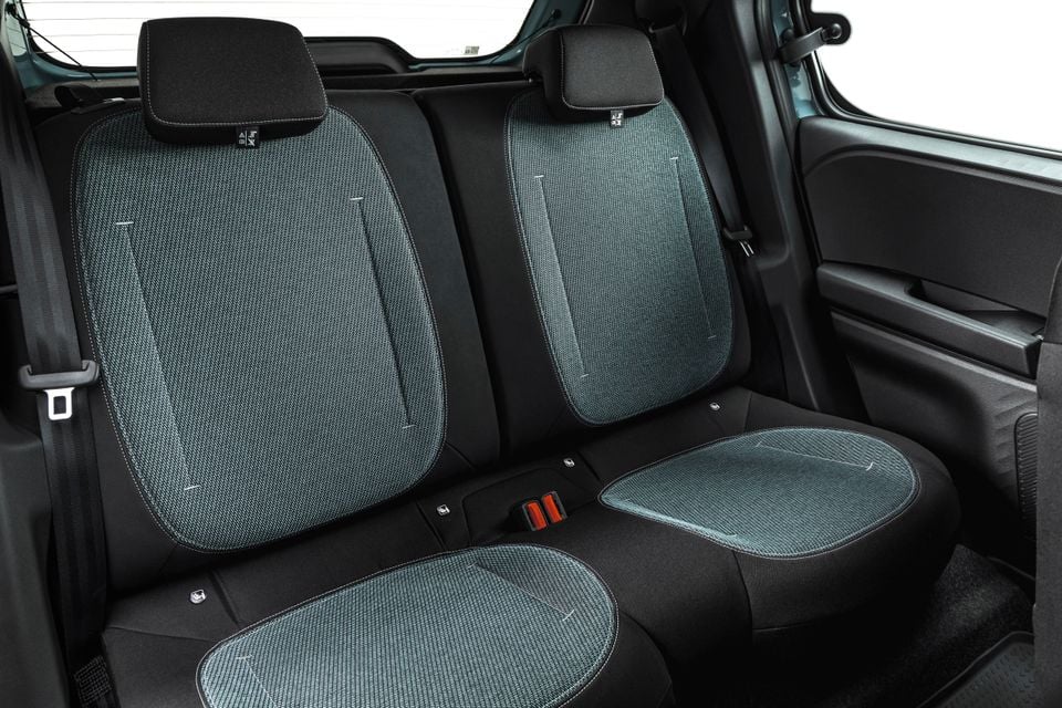 Rear seats of the 2027 Dacia Spring showing blue-grey fabric upholstery with white contrast stitching and black trim