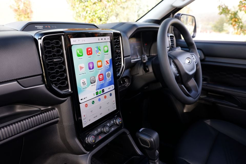 Interior of a Ford Everest showing a large vertical touchscreen infotainment display with Apple CarPlay active, the steering wheel, and centre console