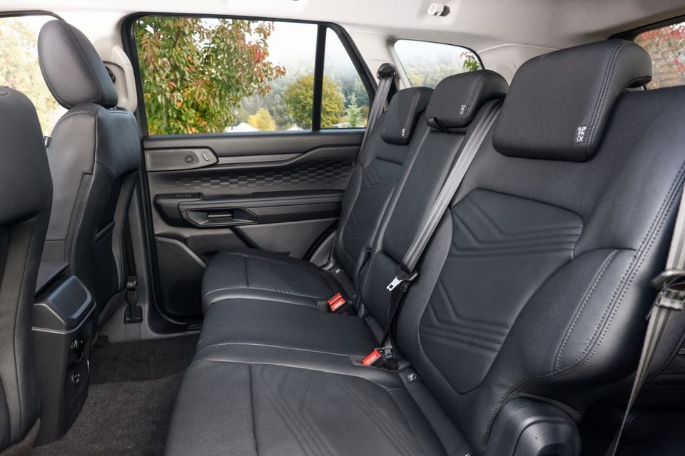 Rear interior of a 2027 Ford Everest Active showing black leather second-row seats with seatbelts and door trim detail