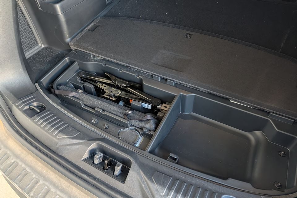The under-floor storage compartment of a 2027 Ford Everest Active's boot, open to reveal a scissor jack and toolkit
