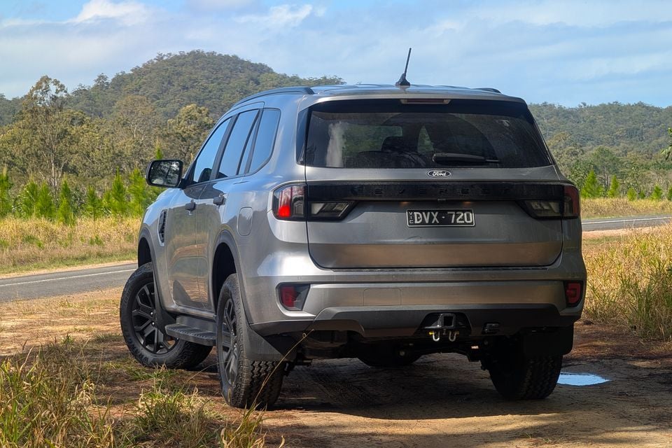 Rear view of a silver Ford Everest SUV parked on a dirt roadside with Australian bushland in the background