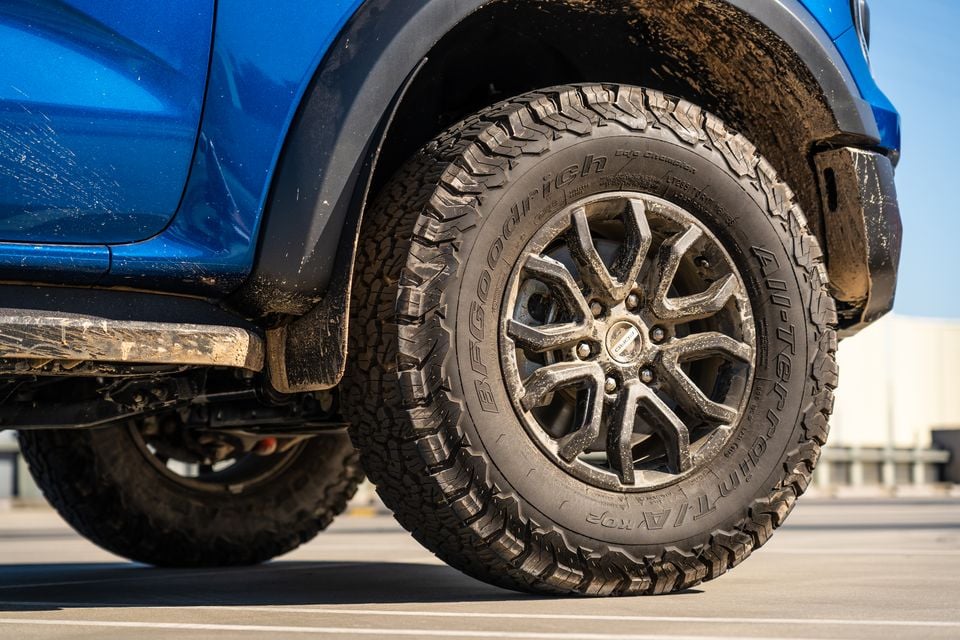 A close-up view of a mud-splattered wheel and tyre on a blue Ford Ranger Raptor