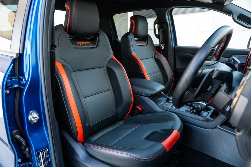 The black and red front seats of a 2024 Ford Ranger Raptor, viewed through the open driver's door.