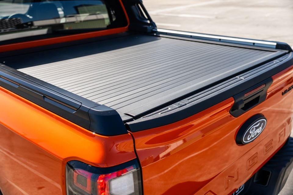 Close-up of the tray and roller cover on an orange Ford Ranger Wildtrak ute, showing the tailgate with Ford badge and Ranger lettering