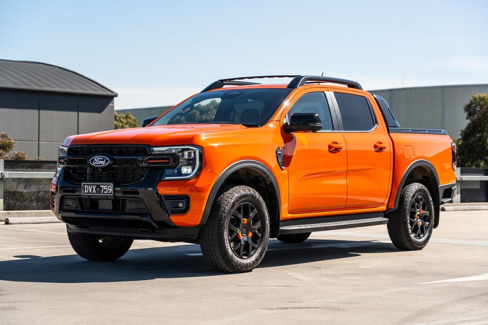 An orange Ford Ranger Wildtrak dual-cab ute seen from the front-side in a car park