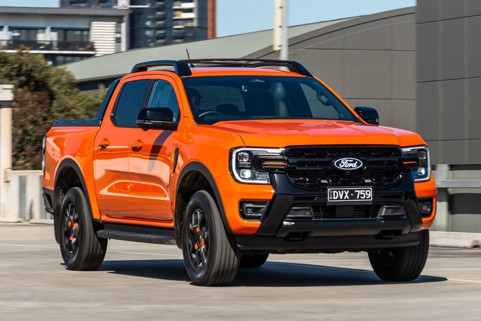 An orange Ford Ranger Wildtrak dual-cab ute seen from the front-side angle in an urban setting