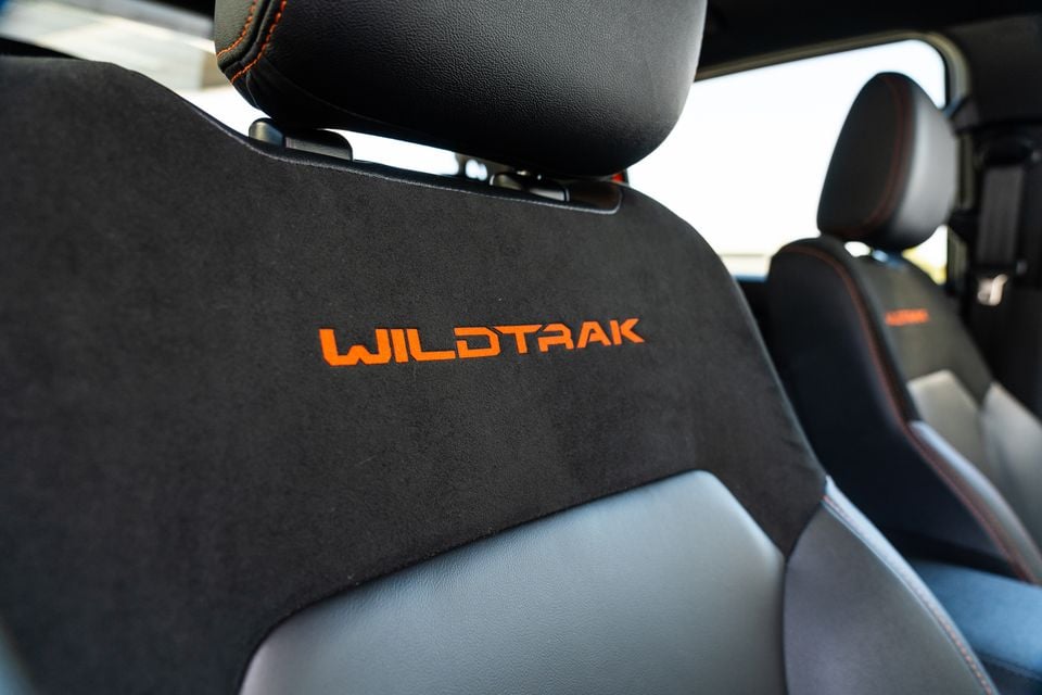 Ford Ranger Wildtrak front seat interior showing orange 'Wildtrak' embroidery on black suede-style upholstery with orange contrast stitching