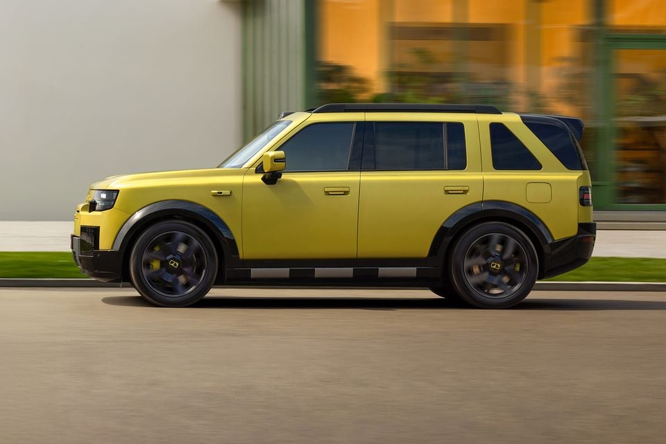 A yellow Land Rover Freelander SUV photographed from the side while driving on a street