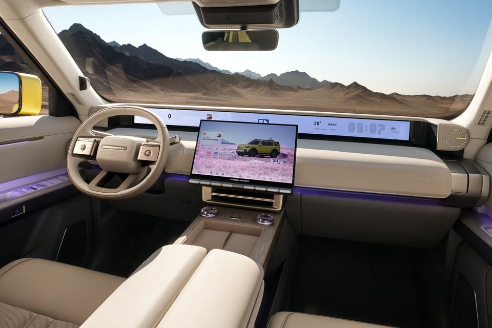 The interior of a Freelander concept SUV showing a wide digital dashboard, steering wheel and central touchscreen, with a desert mountain landscape visible through the windscreen.