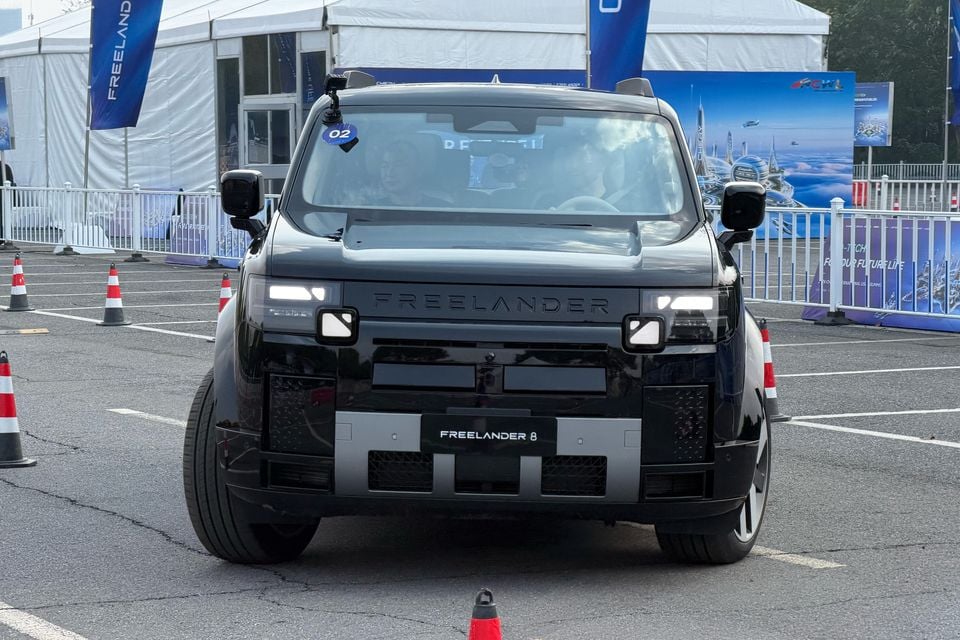 Front view of the black Freelander 8 with its lights on