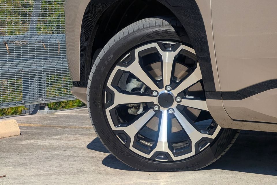 Close-up of a machined alloy wheel on a tan GAC Aion V SUV parked on a concrete surface